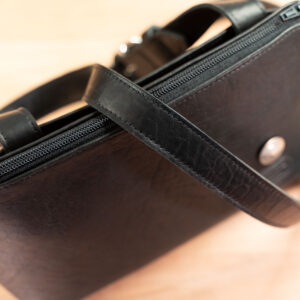Adjustable leather strap laid across the top of the black Southern Prairie Crossbody Leather Purse